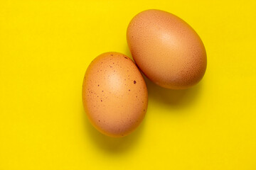 Brown chicken eggs on yellow background. Fresh chicken eggs background. Top view with copy space
