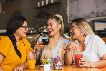 Three friends smiling while having a coffee in a bar