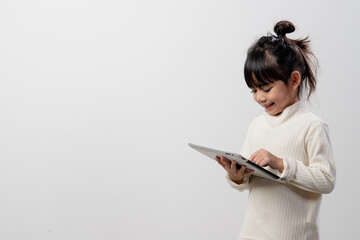 Asian little girl holding and using the digital tablet on white studio background, free copy space