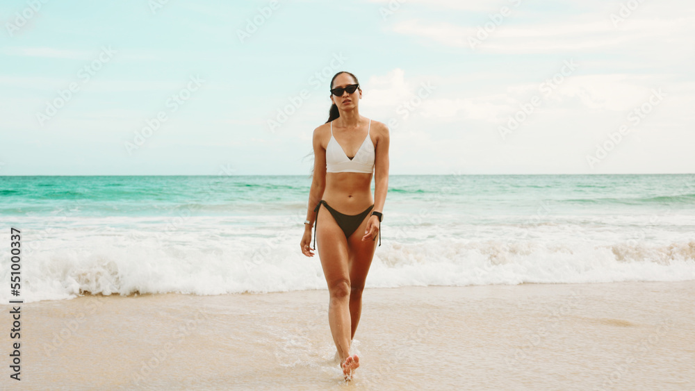 Wall mural A Sensual Model Asian woman tan skin in bikini walking on the beach