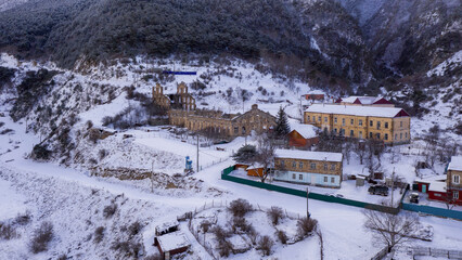 Aerial view of Fasnal village and remains of concentrating factory (monument of history and architecture late 19th century) on winter evening. Digoria, North Ossetia, Russia.
