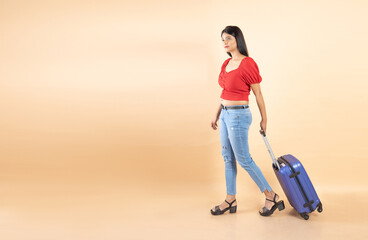 Young Indian Asian woman wearing casual being ready to go on vacation traveling trip with travel trolly bag luggage isolated over beige background, Studio shot,. People lifestyle, copy space.