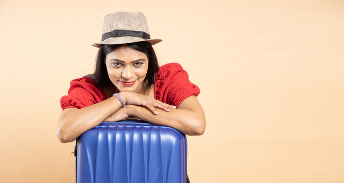 Young Indian couple with travel trolly bag luggage ready to go on vacation holiday traveling trip, isolated over beige background, copy space, studio shots. Closeup,