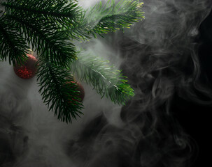 Green branches of a fir tree with Christmas tree toys shrouded in clouds of smoke on a black background