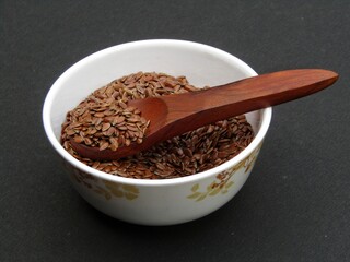 Flax seeds in a bowl on black background 