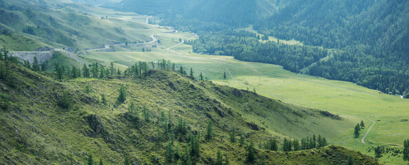 The road descends into the mountain valley, morning light, panoramic view