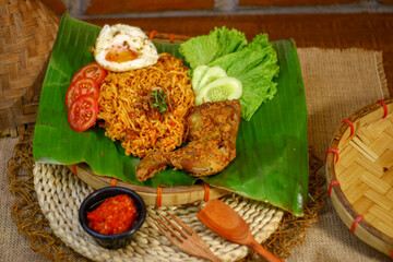 spicy noodle food with additional omelet and fried chicken packaged on banana leaves in a classic and traditional style
