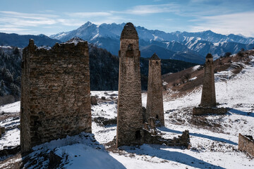 Medieval Ingush towers complex Niy against Caucasian Range on sunny winter day. Ingushetia, Russia.