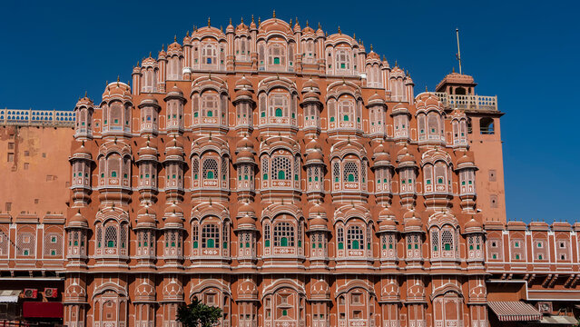 Beautiful ancient Palace of the Winds- Hawa Mahal. The five-tiered building in the form of the crown of Krishna is made of red sandstone. There are many windows with openwork grilles on the facade. 