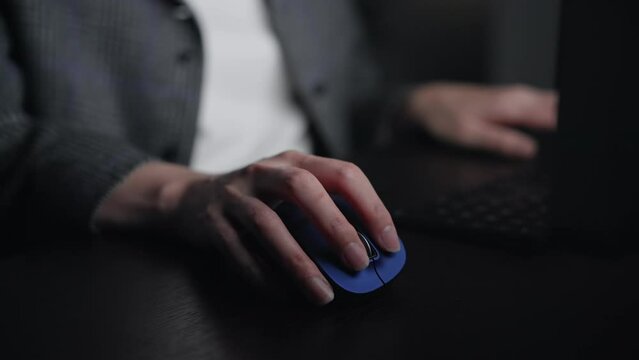 Scene of an anonymous person using a computer in a dark room.