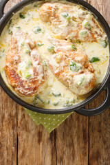 Homemade Chicken breast stewed in Mexican creamy sauce with vegetables close-up in a frying pan on a wooden table. Vertical top view