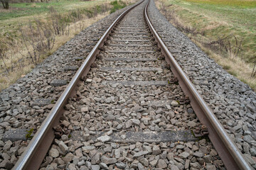 Long railway track in the countryside with dry grass on the sides 