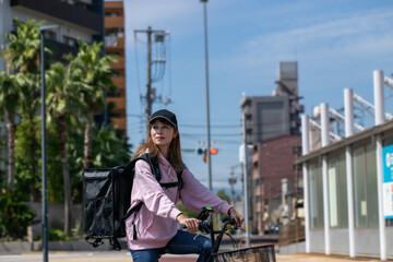 自転車で配達するフードデリバリーの女性