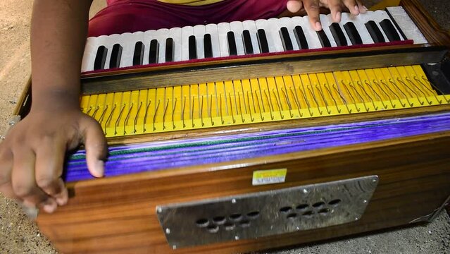 Close up shot of a musician playing Indian traditional musical instrument harmonium.