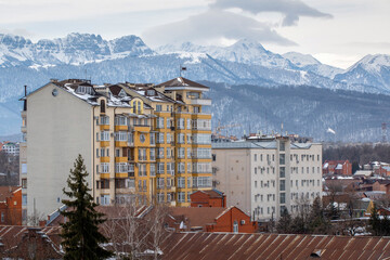 Residential buildings on the background of Caucasian mountains on cloudy winter day. Vladikavkaz, North Ossetia, Russia.