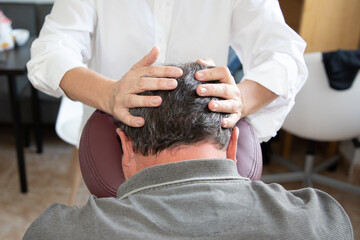 Massage therapist man massaging male head skull sitting on massage seated by woman specialist on...