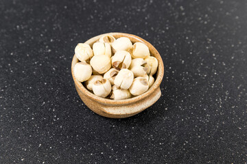 Lotus seeds in a ceramic bowl on a black cutting board top down view