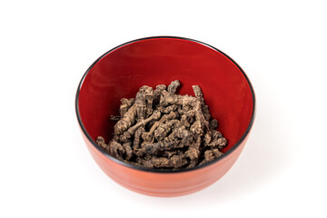 Valerian roots in a red and black bowl isolated over white