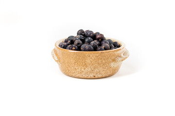 Juniper berries in a ceramic bowl isolated over white