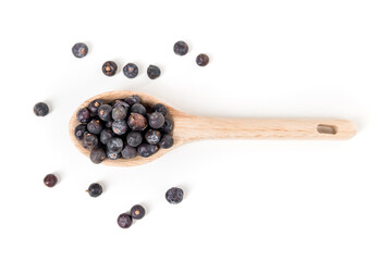 Juniper berries scattered around a wood spoon isolated over white top down