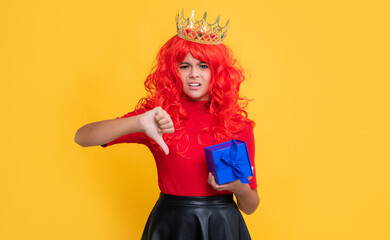 unhappy child in diadem with present box on yellow background