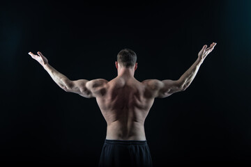 muscular bodybuilder in black studio. strong bodybuilder has muscular back muscles.
