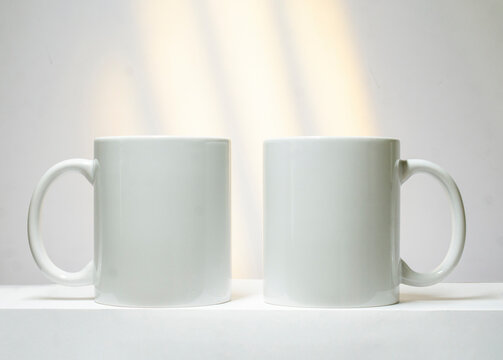 Mockup of white mugs, two white mugs on a white background to insert an image