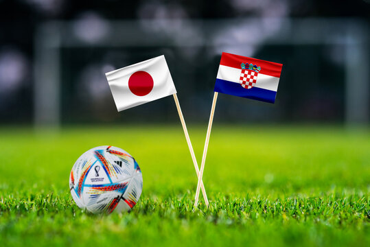 QATAR, DOHA, DECEMBER 2. 2022: Japan - Croatia Round of 16 football match. Official ball of Fifa world cup Qatar 2022 on green grass. Soccer stadium in background. Handmade national flags.