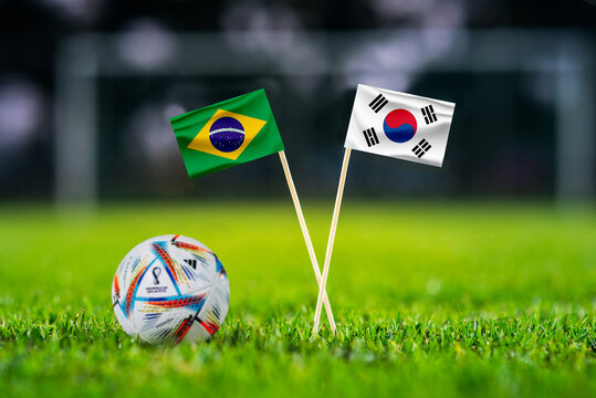 QATAR, DOHA, DECEMBER 2. 2022: Brazil - South Korea Round of 16 football match. Official ball of Fifa world cup Qatar 2022 on green grass. Soccer stadium in background. Handmade national flags.