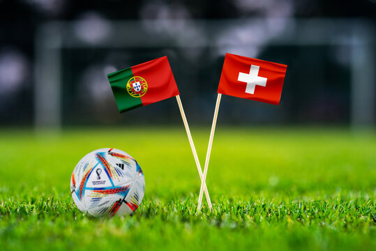 QATAR, DOHA, DECEMBER 2. 2022: Portugal - Switzerland Round of 16 football match. Official ball of Fifa world cup Qatar 2022 on green grass. Soccer stadium in background. Handmade national flags.