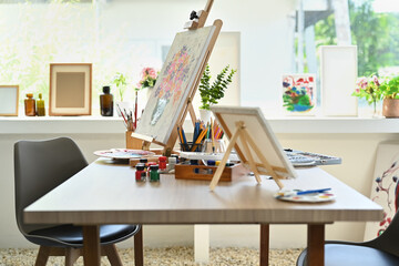 Artist studio interior with canvas, paint brushes, tubes of paint on wooden table. Painters room...
