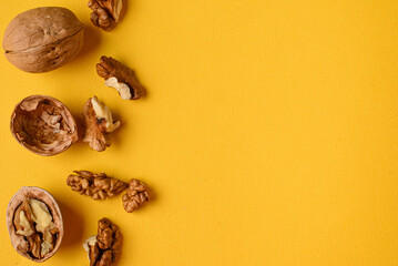 Some of whole and broken  with shell walnuts on a bright yellow plain background clouse up with copy space