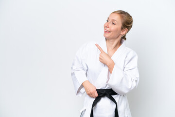 Young caucasian woman isolated on white background doing karate and pointing to the lateral
