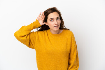Young caucasian woman isolated on white background listening to something by putting hand on the ear
