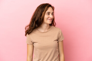 Young caucasian woman isolated on pink background looking side