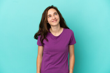 Young caucasian woman isolated on blue background thinking an idea while looking up