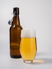 Glass and bottle of beer on a white background. Glass of light beer with foam.