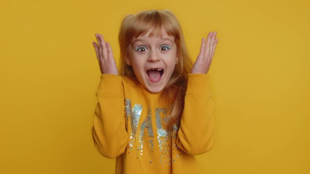 Oh my God, Wow. Young preteen child girl kid looking surprised at camera with big eyes, shocked by sudden victory, game winning lottery goal achievemen good news. Toddler children on yellow background