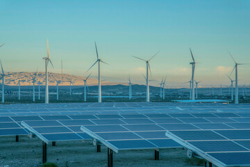 Desert wind farm near mountains with solar panels and wind turbines in California