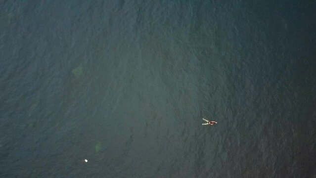 Plan a&eacute;rien d'une femme qui nage dans la mer, jusqu'&agrave; r&eacute;v&eacute;ler tout le bord de mer
