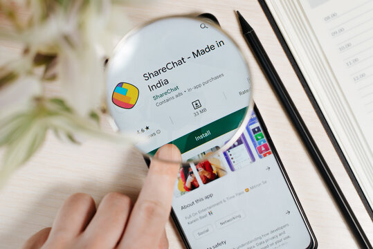 Sharechat Indian social networking service mobile application in Google Play online store on smartphone screen on table, view through magnifying glass. Smolensk, Russia 02.12.2022