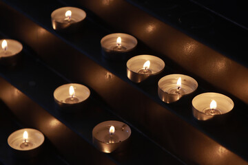Many burning candles in the church - 551042972
