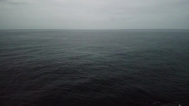 Aerial cloudy sea. Drone view of peaceful calm dark blue sea water surface, cloudy sunset or sunrise sky and silhouettes of mountains. Storm Large freight dark gloomy rain clouds over a calm sea.
