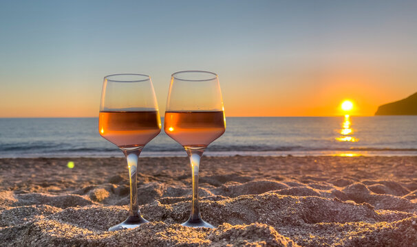 Wineglasses on the beach at sunset- travel,  romance,  new year concept