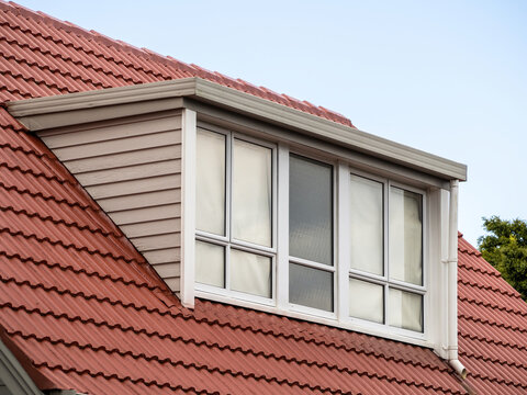 Shed dormer loft with glass wall on red tiled roof.