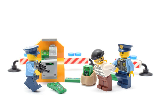 Lego minifigures of fighting criminal and police officer are standing in front of cashpoint. Editorial illustrative image of law and punishing. Studio shot.
