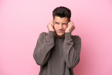 Young caucasian man isolated on pink background frustrated and covering ears