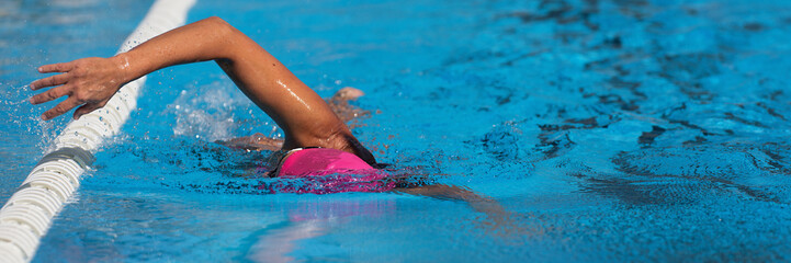 Swimmer woman athlete swimming in pool lanes doing a crawl lap. Swim race freestyle. Triathlete...