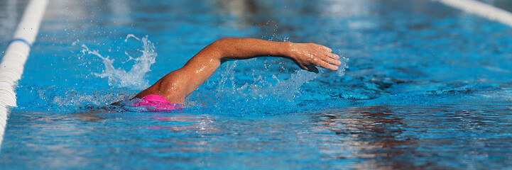 Swimmer man athlete swimming in pool lanes doing a crawl lap. Swim race freestyle. Triathlete...