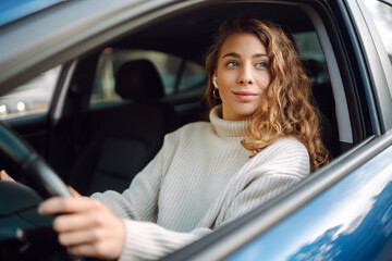 Pretty woman driver smiling to you from the  car. Automobile Journey, traveling, lifestyle concept. Car sharing.